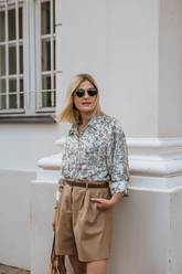 a lady in a blue floral printed shirt and a pair of brown shorts
